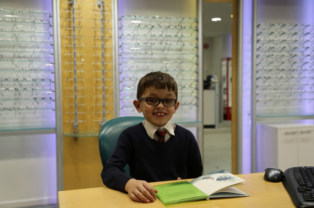 Isaac Randall reading with his coloured overlay following Irlen screening examination/test at Buchanan Optometrists, Kent